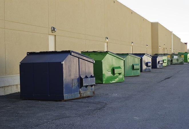 a construction worker unloading debris into a blue dumpster in Hoschton, GA